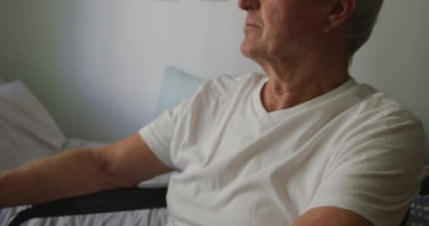 Close up of a senior Caucasian man sitting in a wheelchair, isolating and social distancing in his room at a retirement home during coronavirus covid19 pandemic. - Felvétel, videó