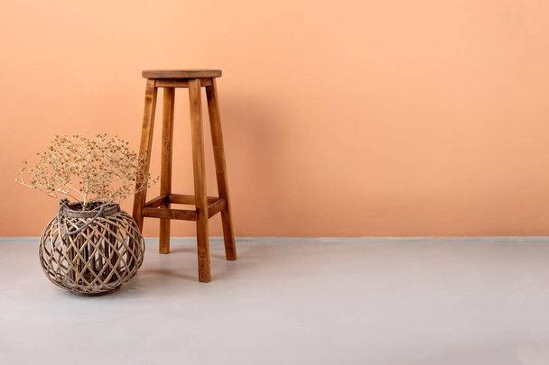 Ψηλά άσπρα πόδια σκαμπό μπαρ είναι το ξύλο σε πορτοκαλί φόντο, μοντέρνα σχεδιαστής καρέκλα δωματίου σε άδειο τοίχο στο απλό εσωτερικό σαλόνι. - Φωτογραφία, εικόνα