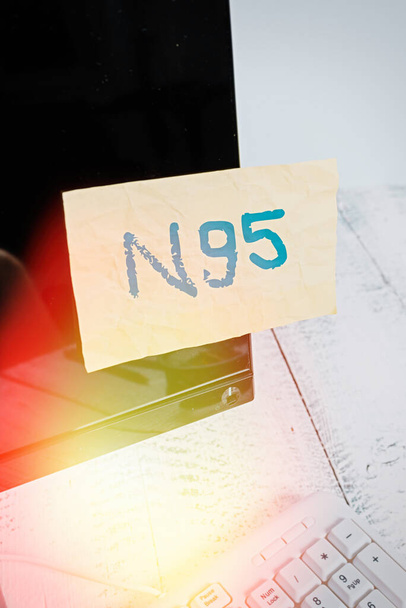 Nota de escritura que muestra N95. Foto de negocios que muestra el equipo de protección personal que se utilizan para proteger al usuario Pantalla de monitor de computadora de papel notación cerca del teclado blanco
. - Foto, Imagen