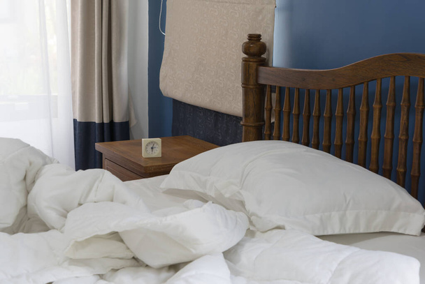 Дерев'яний ліжко збоку стіл і будильник прикрашені в сучасному стилі зі спальнею з бежевим фоном штор
 - Фото, зображення