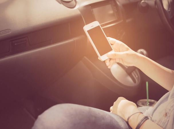 Woman holding mobile phone in car ,retro effect - Foto, imagen