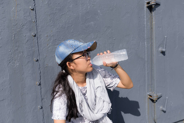 Cute asian girl in trendy style drinking water in sunny day - Photo, Image
