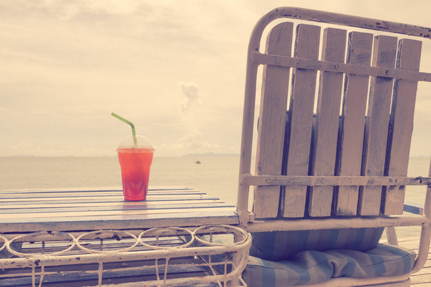 Cold drink on wooden table over summer blue sea,retro effect - Photo, Image