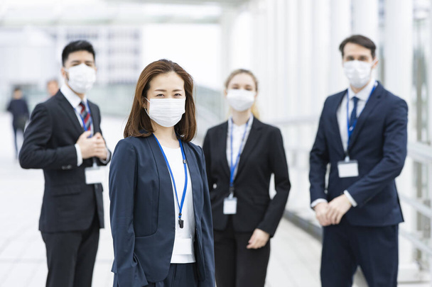 Een team van multinationale zakenmensen met maskers om infectie te voorkomen - Foto, afbeelding