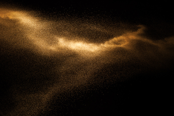 Вибух золотистого піску ізольовано на чорному тлі. Абстрактна піщана хмара
. - Фото, зображення