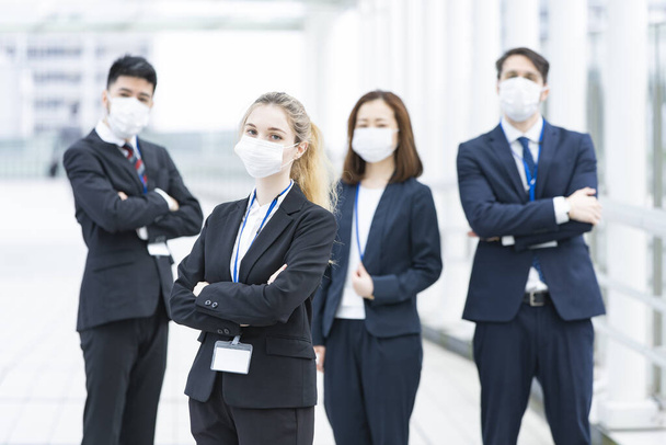 Een team van multinationale zakenmensen met maskers om infectie te voorkomen - Foto, afbeelding