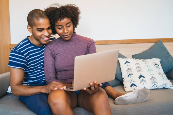 Portrait of happy young couple relaxing and using laptop on couch at home. Lifestyle and relationship concept. - Foto, afbeelding
