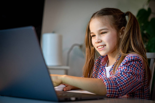 teen girl makes lessons, homework on laptop. - Fotó, kép
