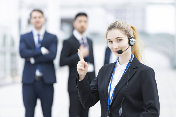 jonge vrouwelijke operator draagt een headset en haar business team - Foto, afbeelding