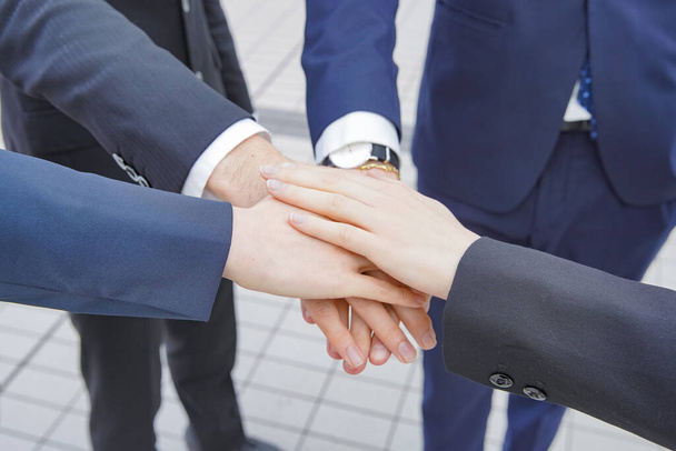Egy csapat üzletember, akik átfedik egymás kezét, hogy erősítsék az egységet. - Fotó, kép