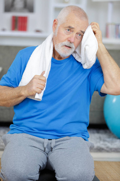 senior man wiping sweat of his forehead with towel - Photo, Image