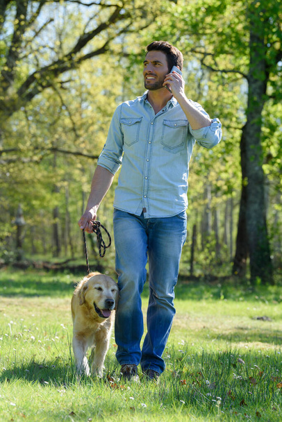man with dog on the phone in the grass - Foto, imagen