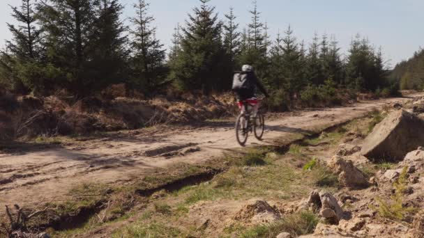 Hombre Mountain Biking por una pista de grava en el campo
 - Metraje, vídeo