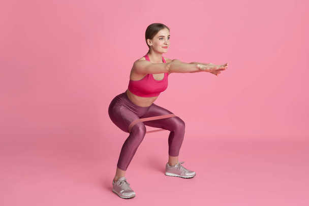 Beautiful young female athlete practicing on pink studio background, monochrome portrait - Foto, imagen