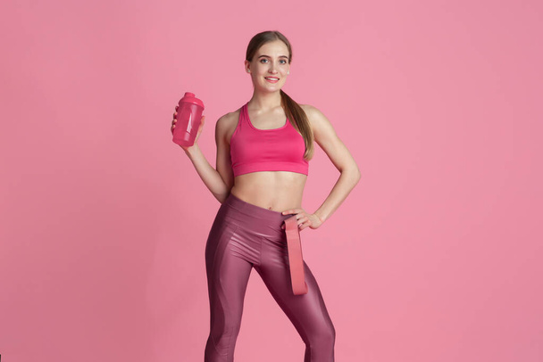 Beautiful young female athlete practicing on pink studio background, monochrome portrait - Photo, Image