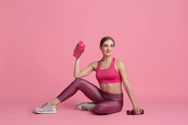 Beautiful young female athlete practicing on pink studio background, monochrome portrait - Zdjęcie, obraz