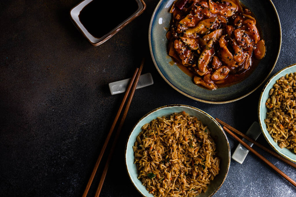 Comida chinesa tradicional com carne de porco doce e azeda e arroz frito servido em um fundo de concreto com espaço de cópia
 - Foto, Imagem