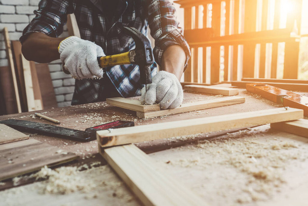 Carpenter working on wood craft at workshop to produce construction material or wooden furniture. The young Asian carpenter use professional tools for crafting. DIY maker and carpentry work concept. - Φωτογραφία, εικόνα