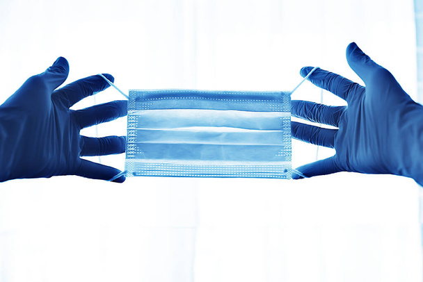 hands putting on a medical mask, concept of virus protection, pandemic, covid-19 - Foto, afbeelding
