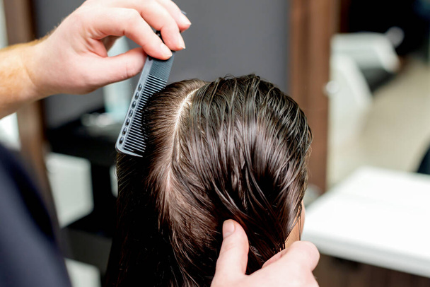 Hand of hairdresser combs wet hair of woman close up. - Foto, Bild