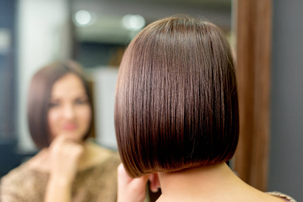 Коротка зачіска жінки, дивлячись у дзеркало в перукарні
. - Фото, зображення