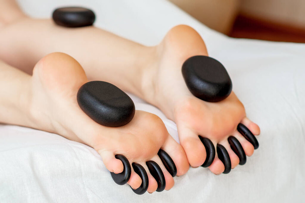Pierres de massage chaudes sur les pieds de la femme pendant le massage des jambes gros plan
. - Photo, image