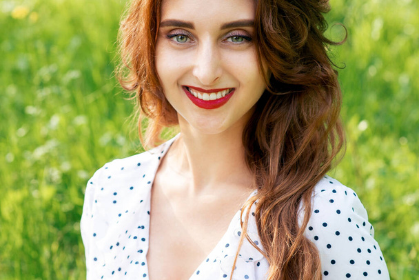 Retrato de una hermosa joven sonriente sobre un fondo verde de naturaleza veraniega
. - Foto, Imagen