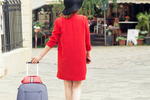 Cestující žena v černém klobouku chůze s kufrem na ulici. - Fotografie, Obrázek