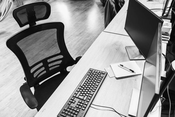 Вид на рабочий стол, два компьютерных экрана, клавиатура, мышь и компьютер имеют черно-белый экран на деревянном столе и офисный фон
 - Фото, изображение