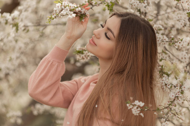 Mooie natuurlijke vrouw tijdens de lente bloesem tijd in kersen tuin. - Foto, afbeelding
