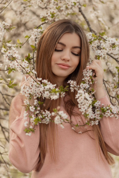 Mooie natuurlijke vrouw tijdens de lente bloesem tijd in kersen tuin. - Foto, afbeelding