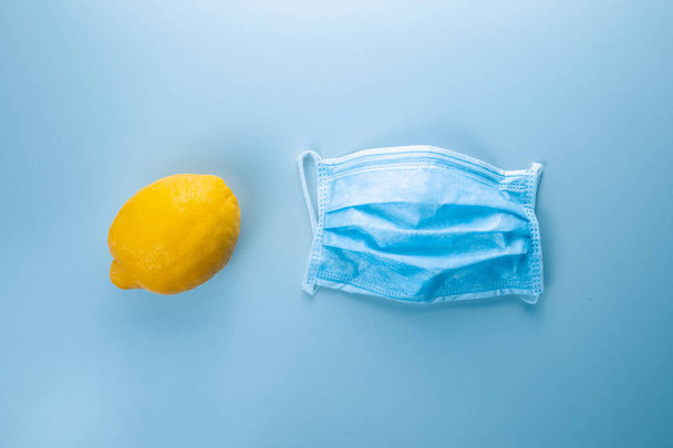 Lemon with sterile mask on blue copy space background - Fotó, kép