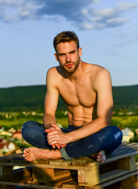 Relaxing after training. sexy man undressed in jeans. male fashion model on sky background. summer relax outdoor. athletic sportsman has sexy body. muscular man at sunset. macho man has naked torso - Photo, image