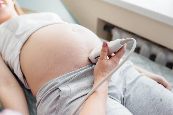 Egy terhes lánynak hasi ultrahangja van a klinikán, közelről. Orvosi vizsgálat - Fotó, kép