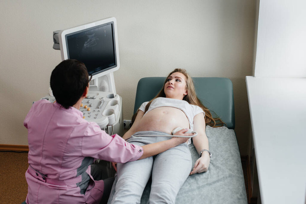 Ciężarna dziewczyna ma USG brzucha w klinice. Badanie lekarskie - Zdjęcie, obraz