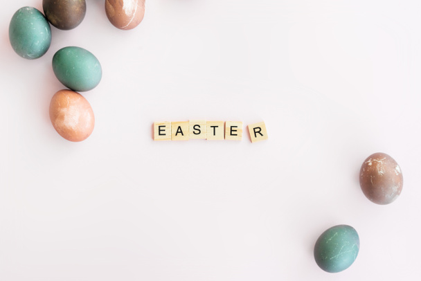 Easter eggs. Word EASTER written on Scrubble letters isolated on pink background, flat lay - Valokuva, kuva