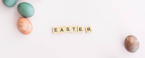 Word EASTER written on Scrubble letters isolated on pink background. painted eggs, banner. Happy easter concept. - Φωτογραφία, εικόνα