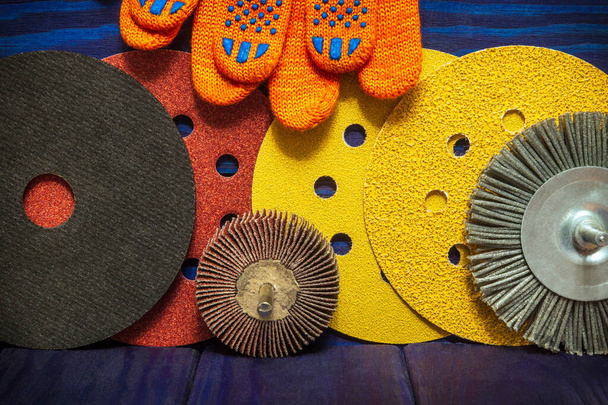 Великий набір абразивних інструментів і помаранчевих робочих рукавичок на синіх вінтажних дерев'яних дошках майстра використовується для шліфування предметів
 - Фото, зображення