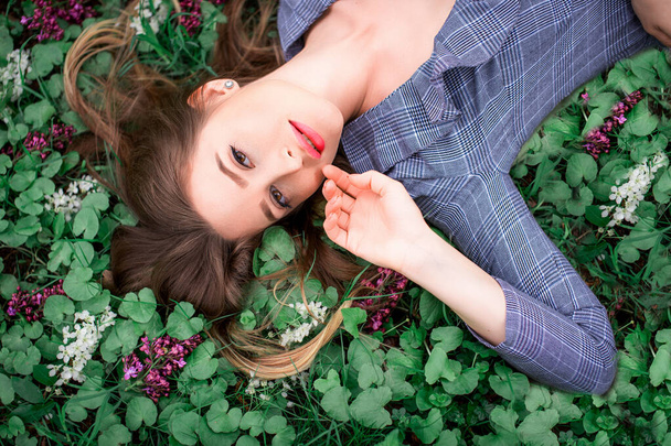 Красивая девушка с рукой лежит на траве в цветах - красота природы
 - Фото, изображение