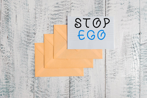 Handschrifttekst Stop Ego. Concept betekent Controle van uw obsessie over een beslissing of een gebeurtenis of iets dergelijks Drie enveloppen rond geregelde papieren vel oude houten vintage achtergrond. - Foto, afbeelding