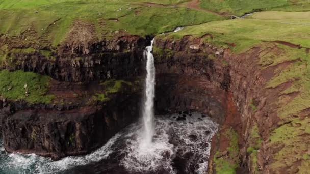 Stunning waterfall splashing from cliff aerial view. Mulafossur waterfall near Gasadalur Village at Faroe Islands. Forward aerial establishing shot, daylight,cloudy weather - Footage, Video