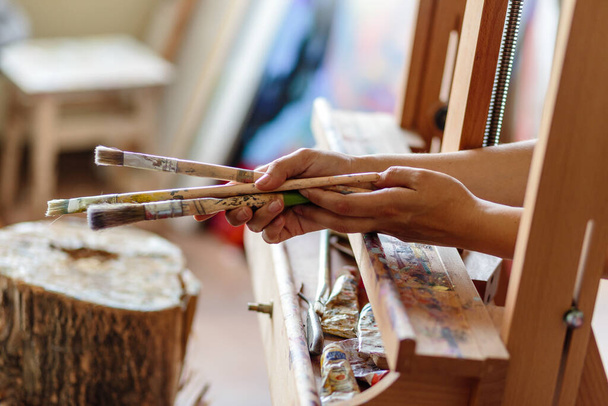 Művész keze ecsettel festéshez festőállványra - Fotó, kép