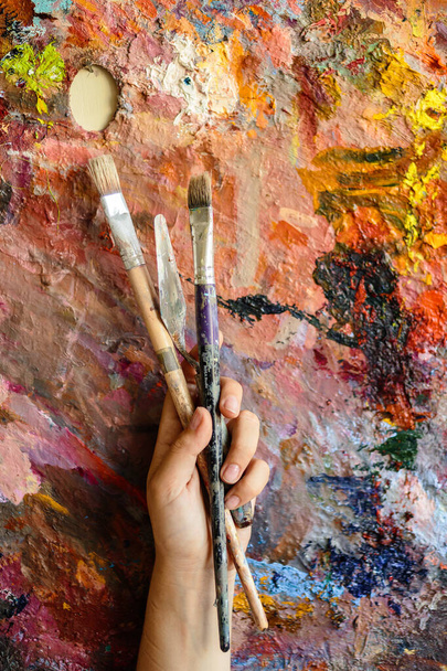 Χέρι καλλιτέχνη με πινέλα για ζωγραφική σε παλέτα χρωματισμένη με έντονα χρώματα - Φωτογραφία, εικόνα
