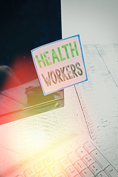 Schreiben Notiz zeigt Health Workers. Geschäftsfotos, die zeigen, wessen Aufgabe es ist, die Gesundheit ihrer Gemeinschaften zu schützen, Notizpapier, das auf einen schwarzen Computerbildschirm in der Nähe von Tastatur und Schreibtisch geklebt wurde. - Foto, Bild