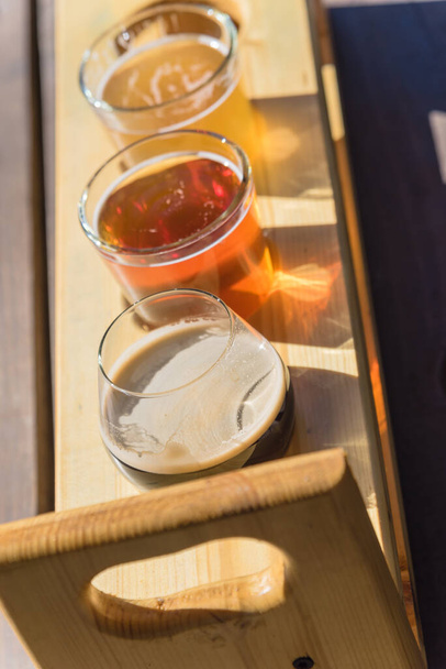 Draufsicht gemischte Fassbiere in Probiertablett auf hölzernem Picknicktisch einer Brauerei in Texas, USA - Foto, Bild