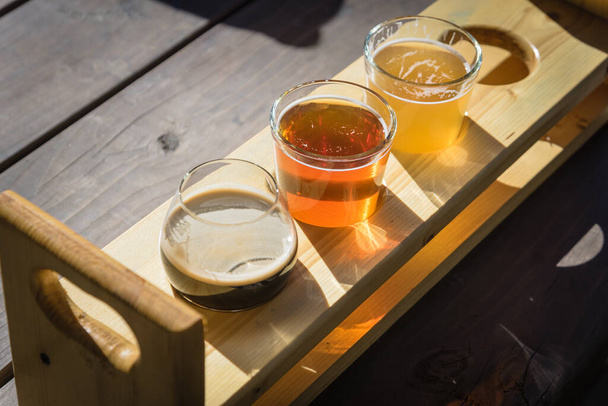 Mixed of hand-crafted beverages on tasting tray paddle with beer name in natural setting - Photo, Image