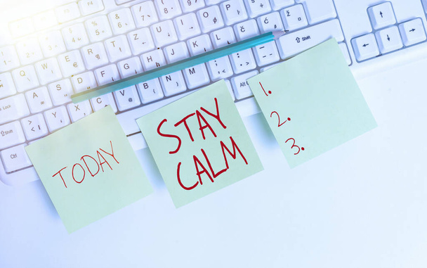 Text sign showing Stay Calm. Conceptual photo Maintain in a state of motion smoothly even under pressure Three empty green square papers and pencil by the pc keyboard with copy space. - Photo, Image
