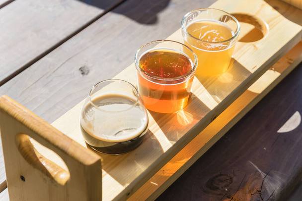Vista superior mista de cervejas rascunho na bandeja sampler de degustação na mesa de piquenique de madeira da cervejaria no Texas, EUA
 - Foto, Imagem