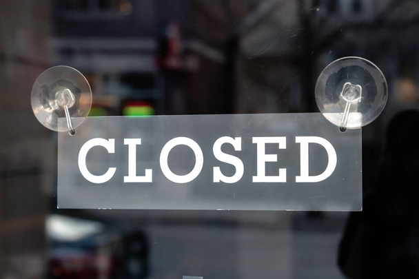 A black and white painted metal sign hangs from two suction cups to a storefront glass door on a store or retail shop in Chicago during the COVID-19 pandemic and stay at home orders. - Photo, Image