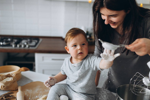 happy family in the kitchen. mother and son preparing the dough, bake cookies - Фото, изображение